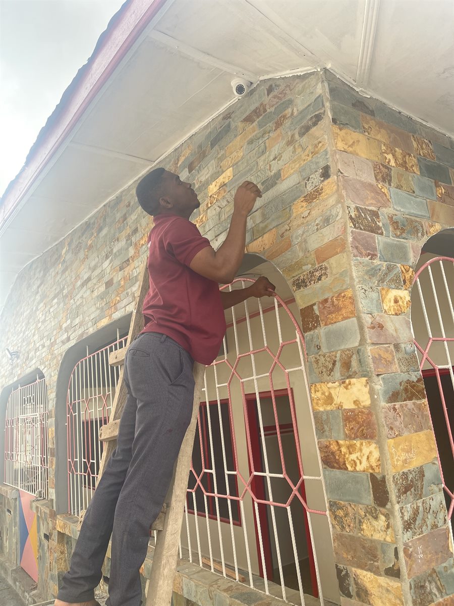 Technician mounting CCTV hardware from a ladder on site.