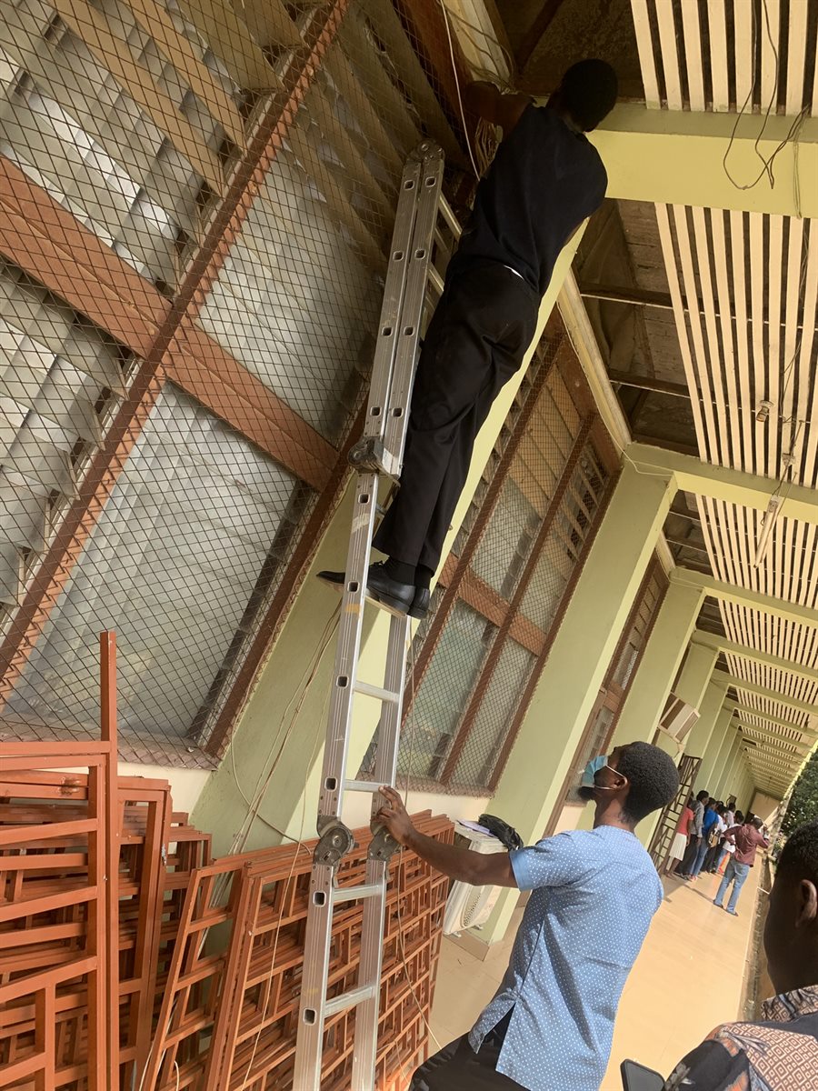 Technician routing cables near the ceiling from a ladder.